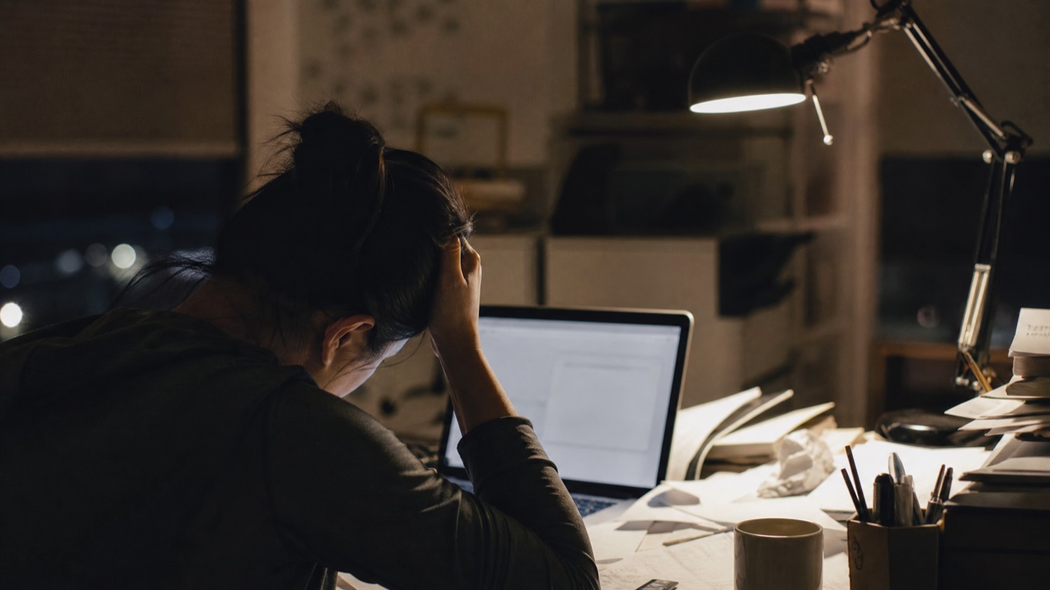 A business owner at a desk late at night, head in hand, worn down by repeated appeal rejections